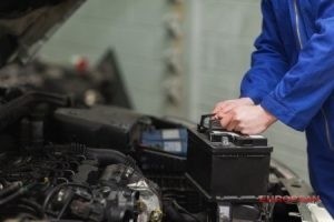 mechanic holds car battery