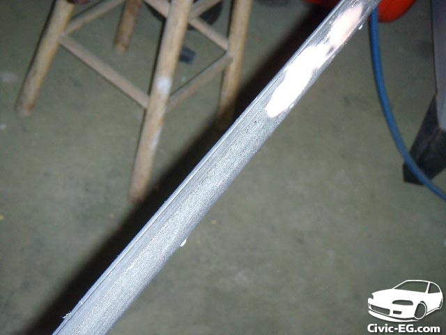 Sanding down the car window trim to remove peeling edges and prepare the surface