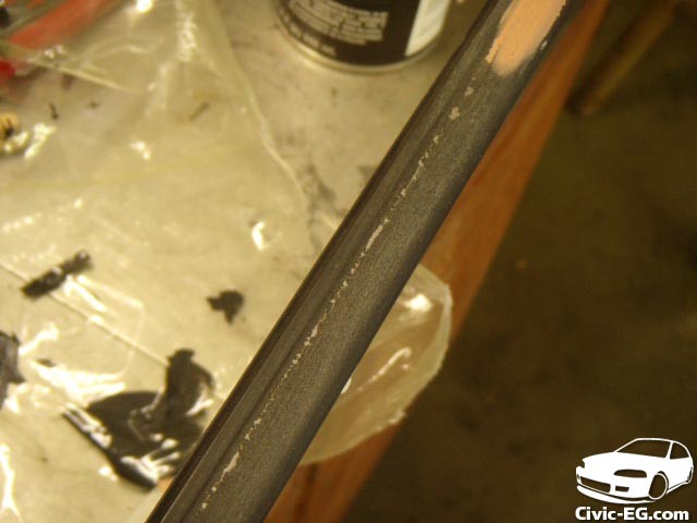 Applying body filler to the auto window trim to fill in imperfections and create a smooth surface