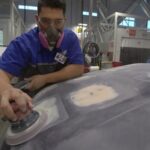 Technician grinding plastic car part