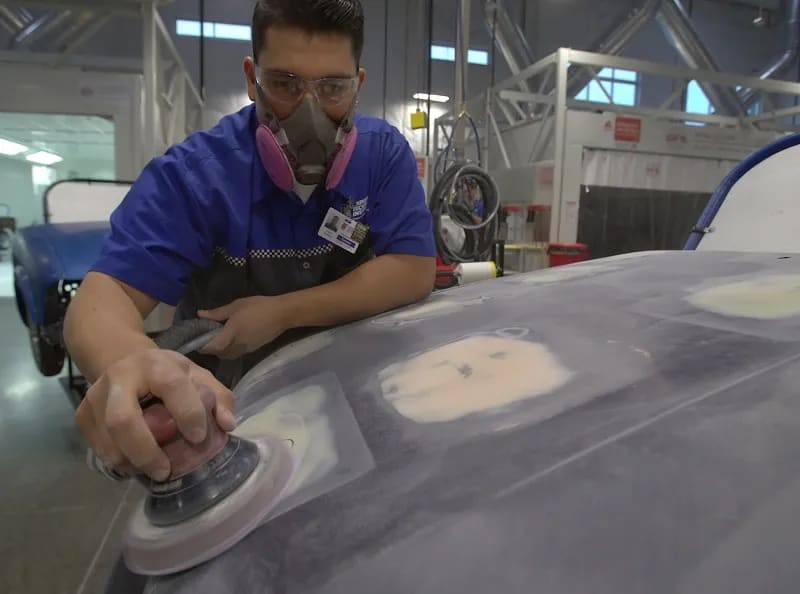 Technician grinding plastic car part