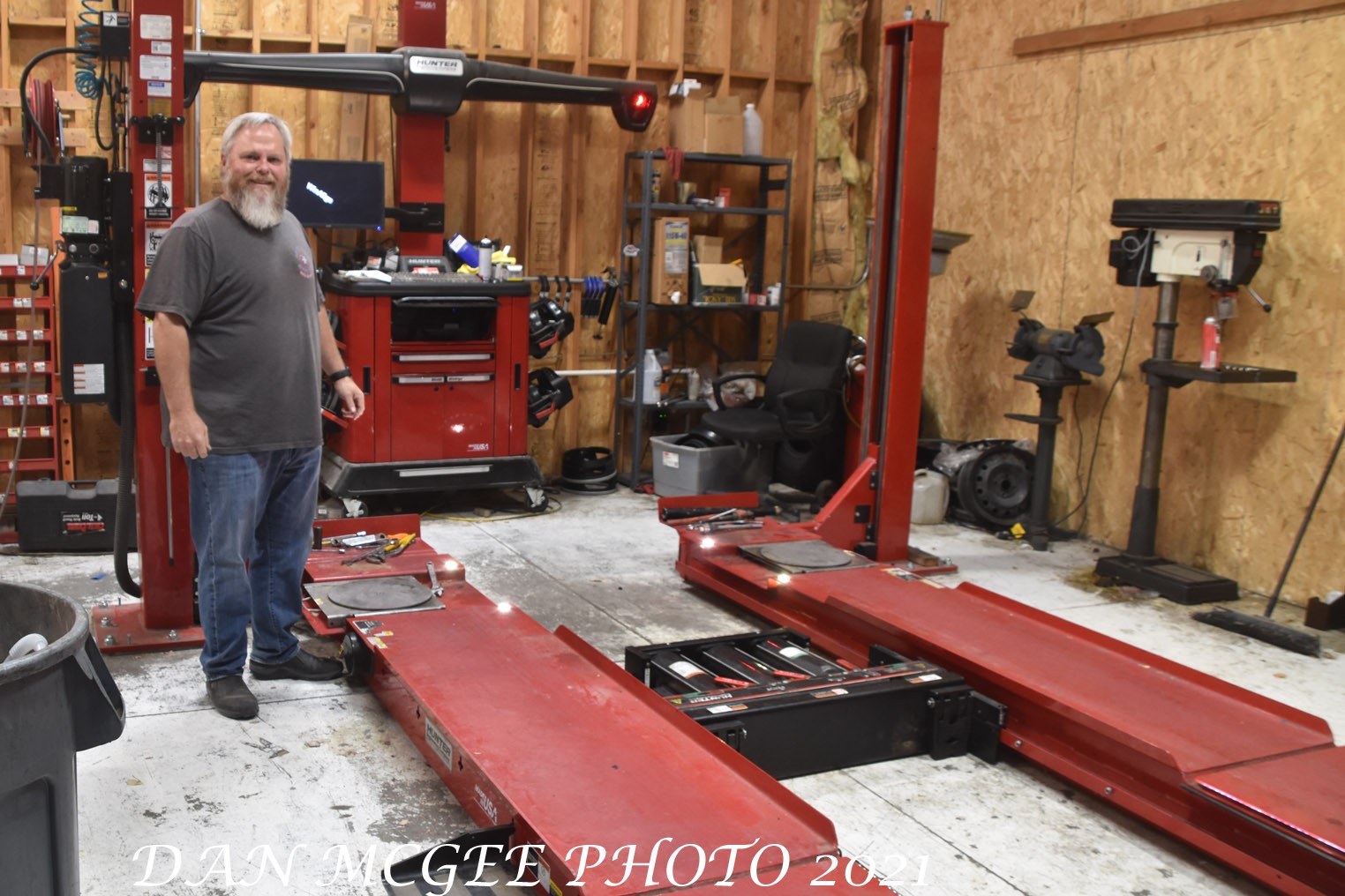 Tom Rankin stands by the state of the art alignment rig at his shop, showcasing the advanced technology used in modern auto repair businesses.